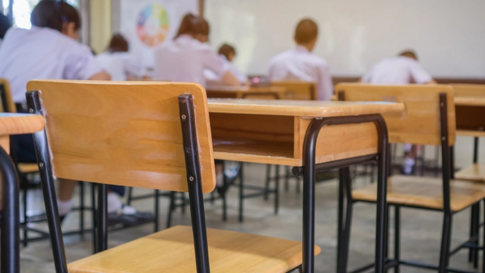 in prim plan o banca goala, iar in plan indepartat, elevi in banci