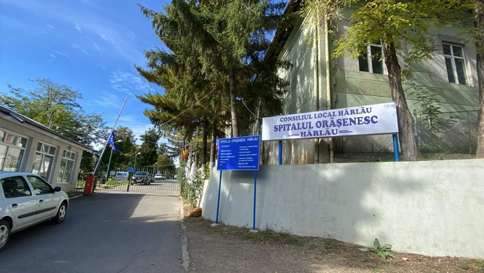 Pancarda Spitalului Orasenesc Harlau cu o masina si copaci la intrare