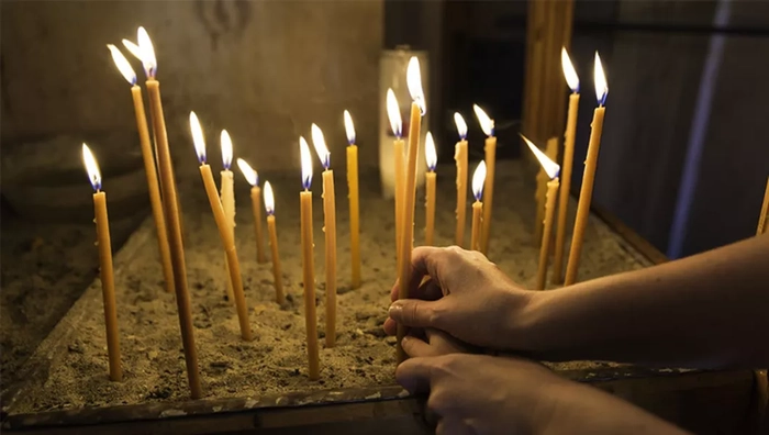 persoana care pune lumanari intr-o biserica