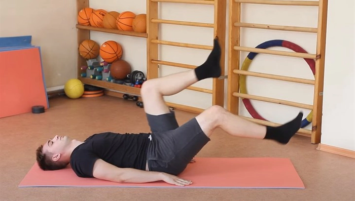 barbat culcat pe un covoras care face gimnastica