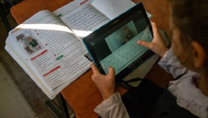 o eleva care scrie pe tableta si un manual pe banca