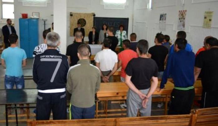 Un grup de persoane care participa la un program de reintegrare sociala intr-o sala cu banci 