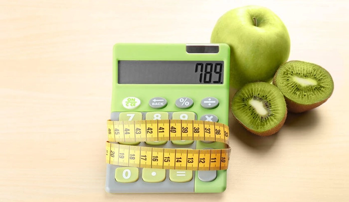 calculator infasurat cu un metru langa mai multe legume pe o masa