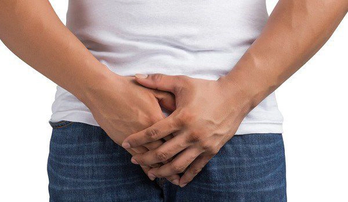 un bărbat în tricou alb cu mâinile în zona intimă