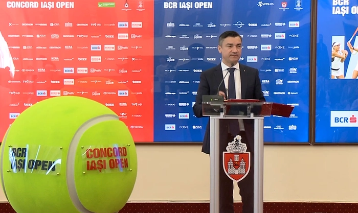 Mihai Chirica la pupitru langa o macheta a unei mingi de tenis