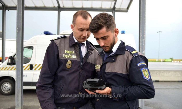 doi politisti din cadrul politiei de frontiera ce se uita pe un dispozitiv electronic