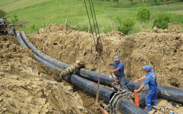 escavator si persoane ce muncesc la o canalizare
