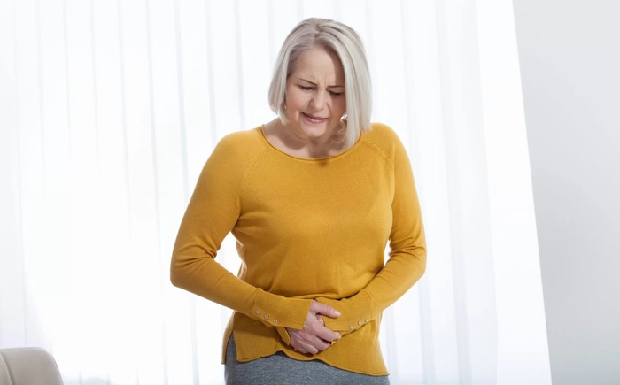 femeie care se tine de zona intima din cauza vezicii urinare inflamate
