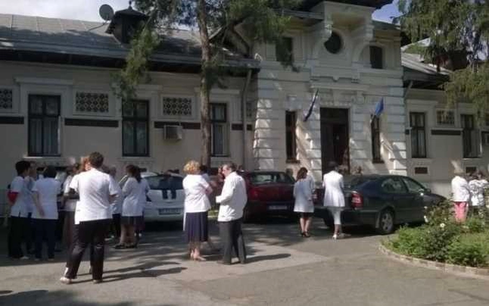 cativa angajati imbracati in halate albe se plimba prin curtea Institutului Socola