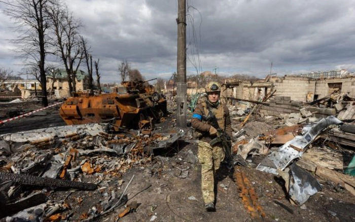 China îndeamnă la reţinere, soldat ce se plimba pe o strada distrusa de bombardamentele rusilor la Bucea Ucraina