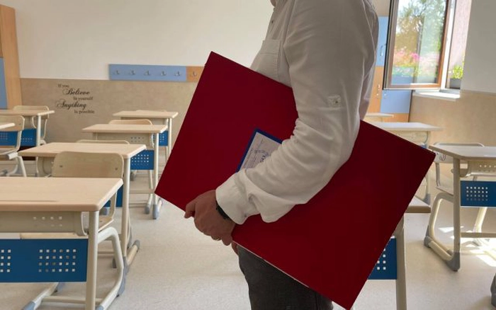 persoana in sala de clasa cu un catalog in mana