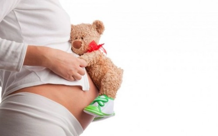gravidă care ține un ursuleț în brațe