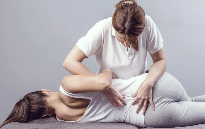 femeie care efectueaza un masaj de reabilitare unei alte femei din cauza unui nerv sciatic blocat