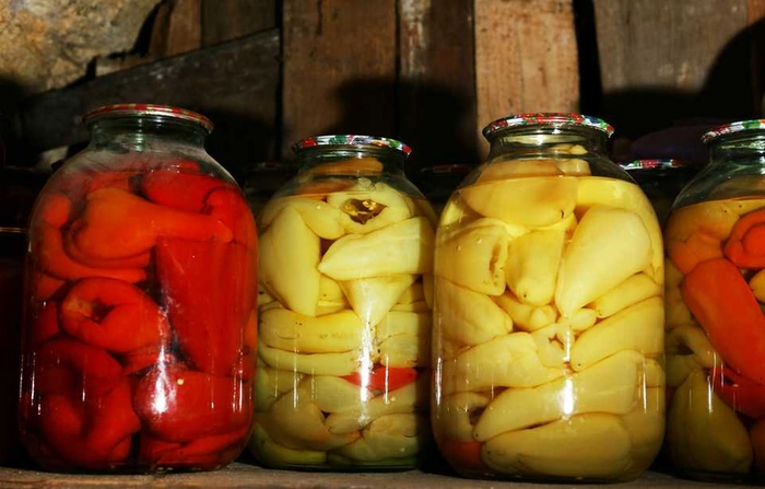 mai multe borcane cu ardei bulgaresti murati pe o masa