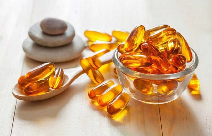 un bol, cu mai multe capsule de omega 3 si o lingura