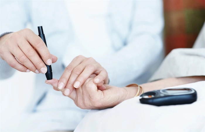 medic care efectueaza un test de sange unei persoane pentru a identifica nivelul de glicemie