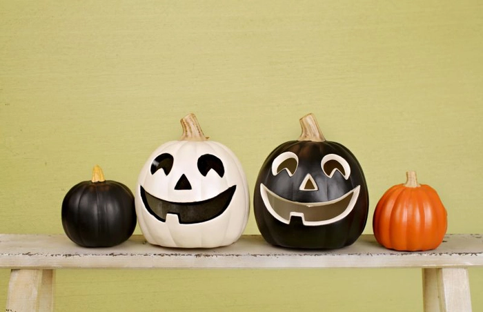 patru dovleci decorati de Halloween pe o banca