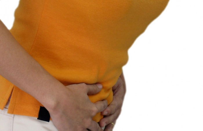 persoana care se tine de burta din cauza durerilor provocate de refluxul gastroesofagian