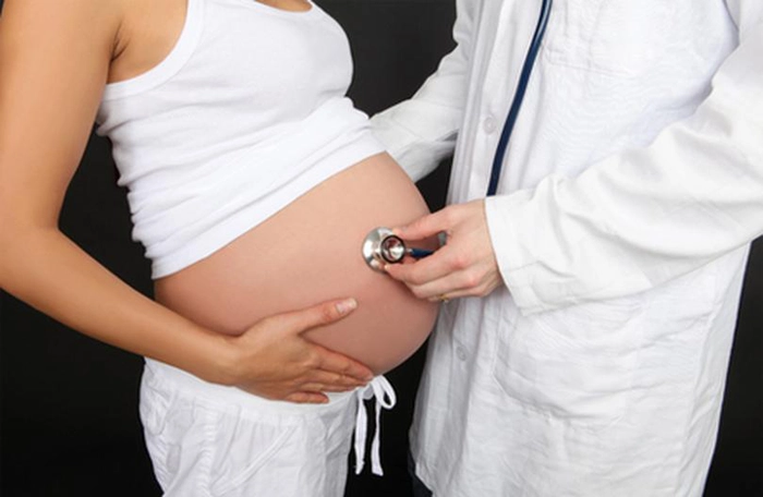 medic care efectueaza un control cu stetoscopul pe burta unei femei insarcinate