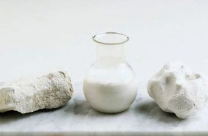 carbonat de calciu in forma de roca si in forma lichida intr-un vas pe o masa
