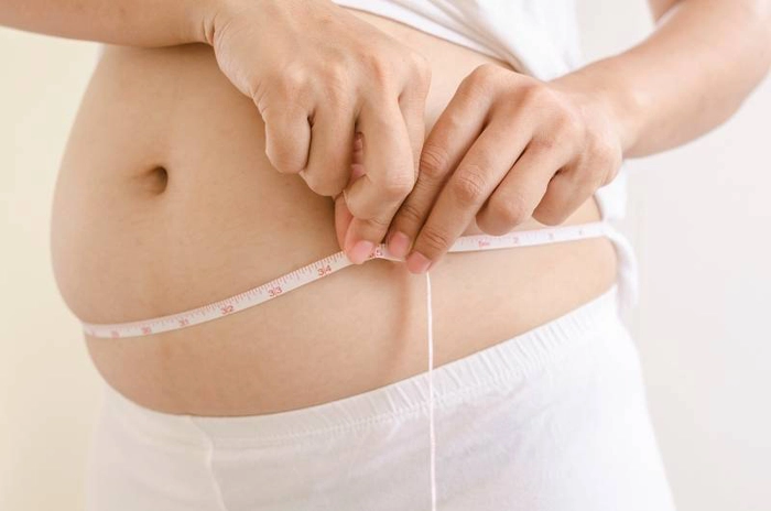 femeie insarcinata care isi masoara cu un metru dimensiunea abdomenului