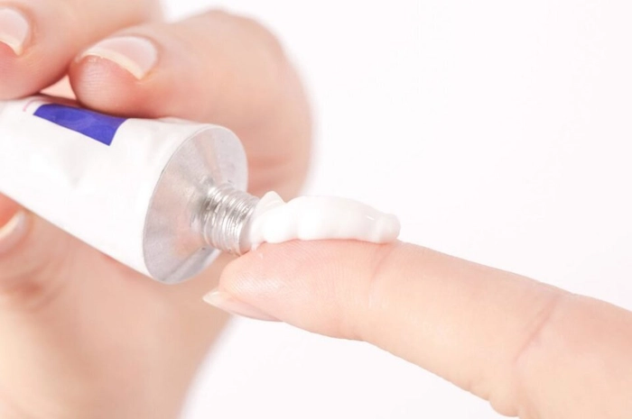 persoana ce toarna crema dintr-un tub