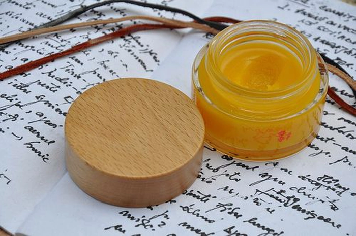 crema de roinita intr-un recipient pe o carte deschisa