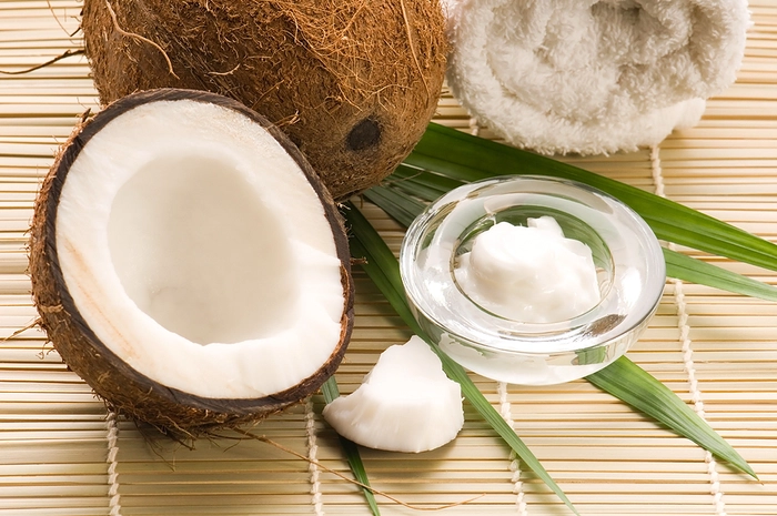 un cocos taiat in doua langa o lingura cu ulei de cocos