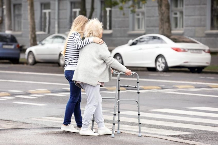persoană cu handicap ajutată să treacă strada