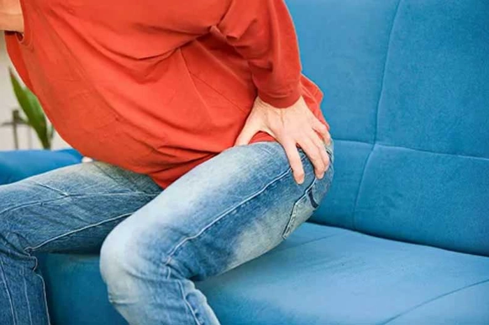 persoana care se tine de picior in timp ce se aseaza