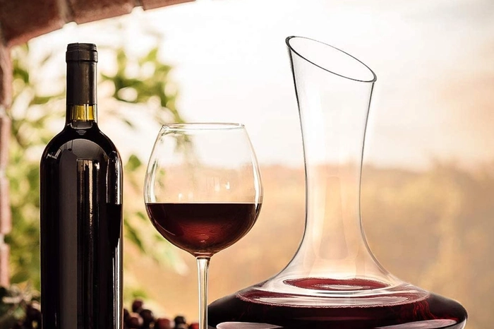 vin rosu servit in pahar langa sticla si carafa