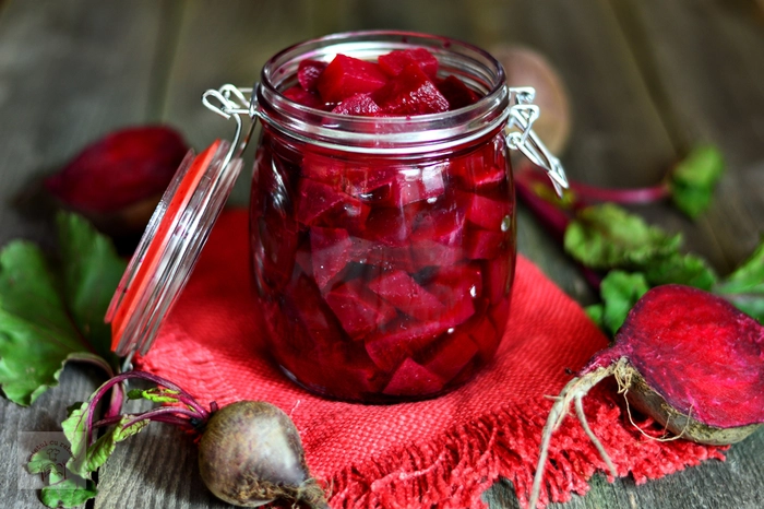 borcan de sticla cu salata de sfecla rosie fiarta pe un prosop rosu