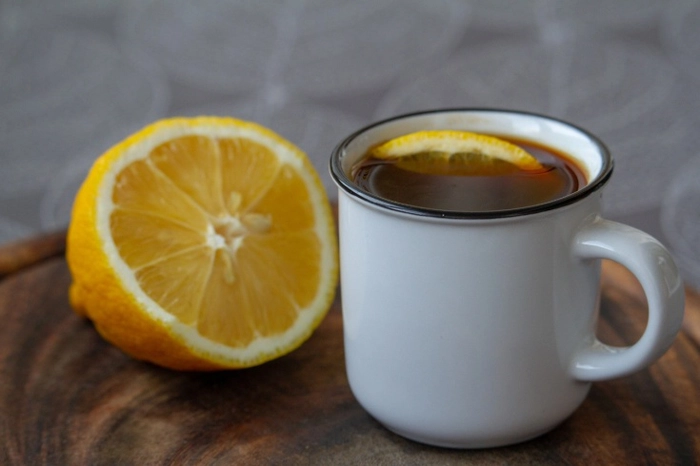 o ceasca de cafea langa o bucata de lamaie pe o masa