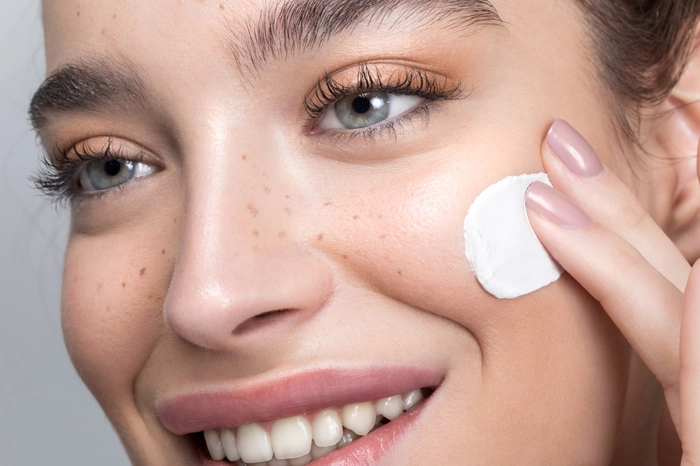 femeie care aplica o crema pentru pete pe fata