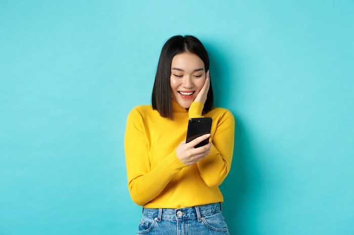 persoana care se uita in telefon si zambeste