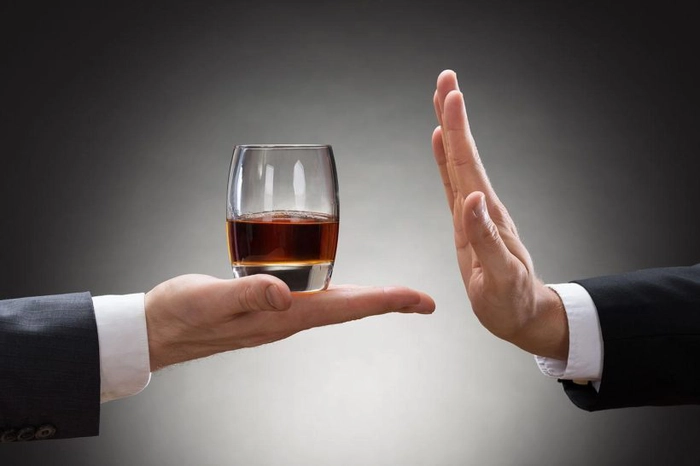  mana unei persoane ce ofera un pahar cu wiskey si mana unei persoane ce refuza