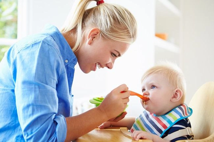 un bebeluș care este hrănit de mama lui cu lingurița