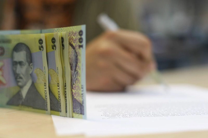 niste bancnote si o mana care scrie pe fundal