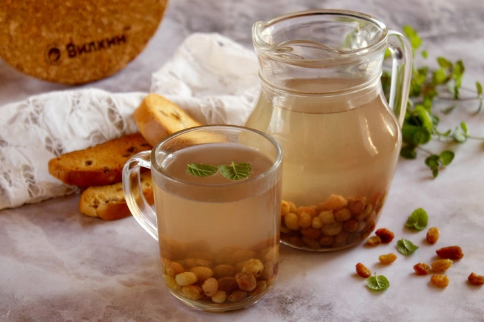 un ulcior cu apa de stafide si o cana plina alturi langa biscuiti pe o masa