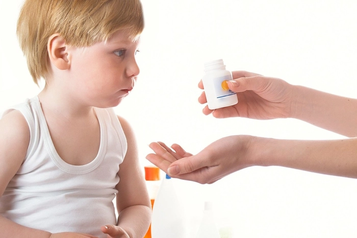 persoana care ii intinde unui copil pastile