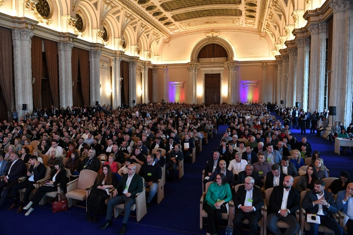 sute de personae pe scaune intr-o sala