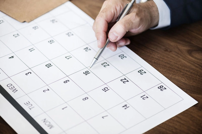 un barbat cu un pix in mana care urmareste ceva intr-un calendar