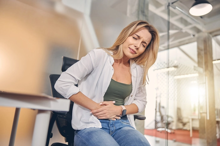 femeie care se tine de burta din cauza durerii provocate de pancreas