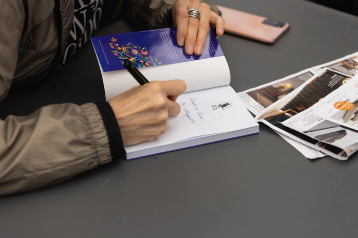 o poză cu un autor care semnează o carte