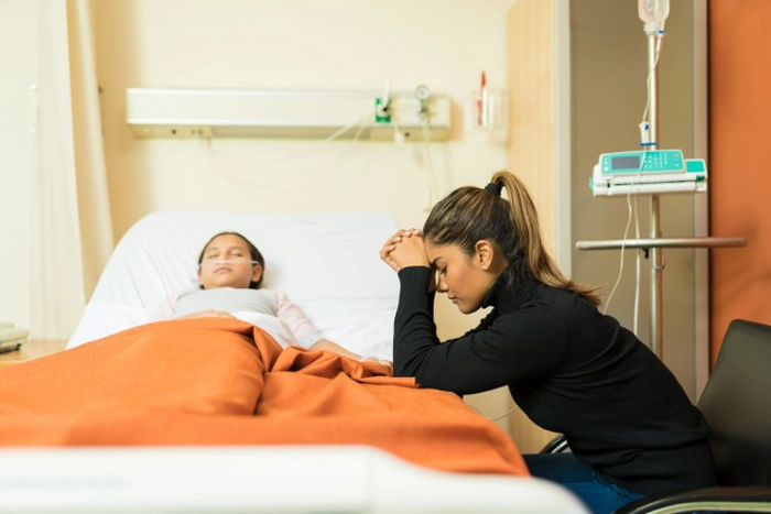 mama care sta ingrijorata langa patul unde se afla copilul bolnav