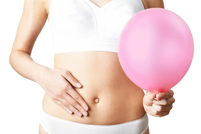 persoana care se tine de burta si tine un balon in mana