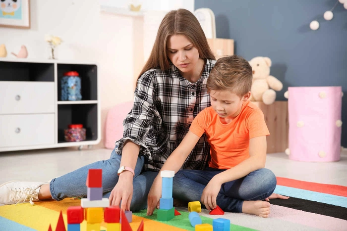 o femeie cu un baietel care se joaca cu jucării de construit