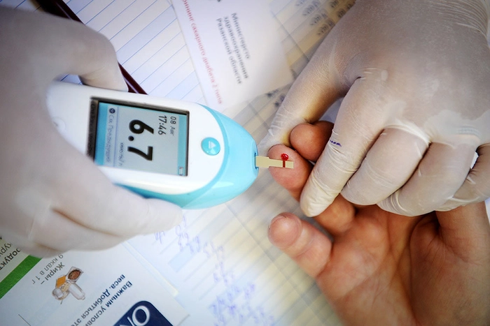 persoana care verifica unei alte persoane nivelul de glicemie din deget