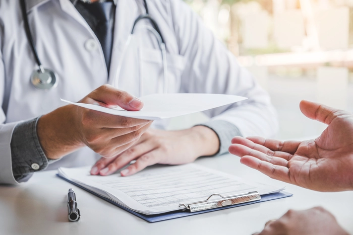doctor ce intinde o prescriptie medicala unui pacient
