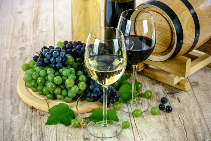 pahare de vin rosu si alb langa chiorchine de struguri alb si rosu